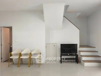 Modern minimalist living room with sleek staircase and TV setup