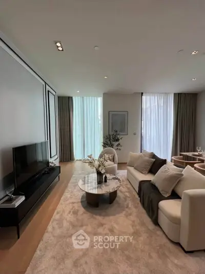 Luxurious living room with elegant decor and natural light, featuring a cozy seating area and modern entertainment setup.