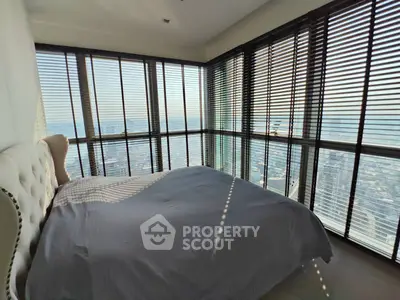 Luxurious corner bedroom with panoramic city views and elegant decor.