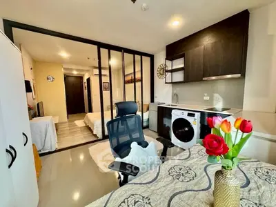 Modern studio apartment with stylish kitchen and cozy living area, featuring a washing machine and elegant decor.