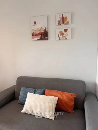 Cozy living room with modern gray sofa and colorful cushions, adorned with stylish wall art.