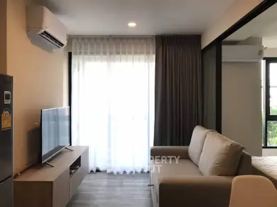 Modern living room with sleek furniture and natural light, featuring a cozy sofa and flat-screen TV.