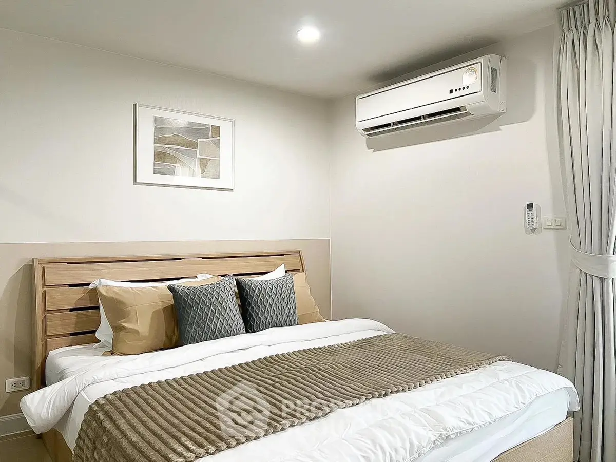 Modern bedroom with stylish decor and air conditioning unit, featuring cozy bedding and elegant wall art.