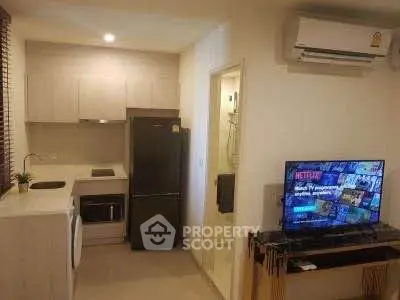 Modern compact kitchen and living area with air conditioning and TV setup.