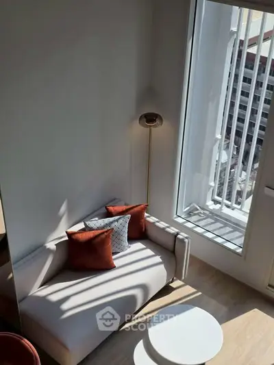 Modern living room with large window and stylish furniture, offering abundant natural light and city views.