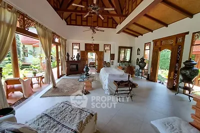 Spacious living room with high wooden ceilings and garden view, featuring elegant decor and natural light.
