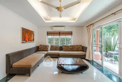 Spacious living room with modern decor and large windows opening to a lush garden view.