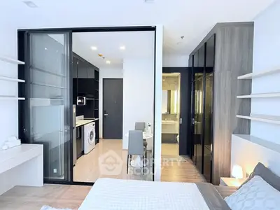 Modern bedroom with open layout, featuring a washing machine and sleek furnishings.