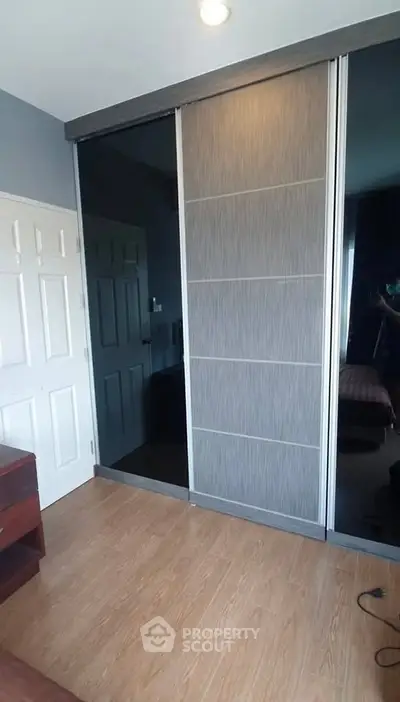 Modern bedroom with sleek sliding wardrobe and wooden flooring