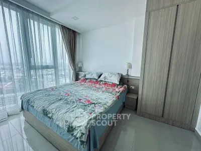 Spacious bedroom with large windows and modern decor in a high-rise apartment.