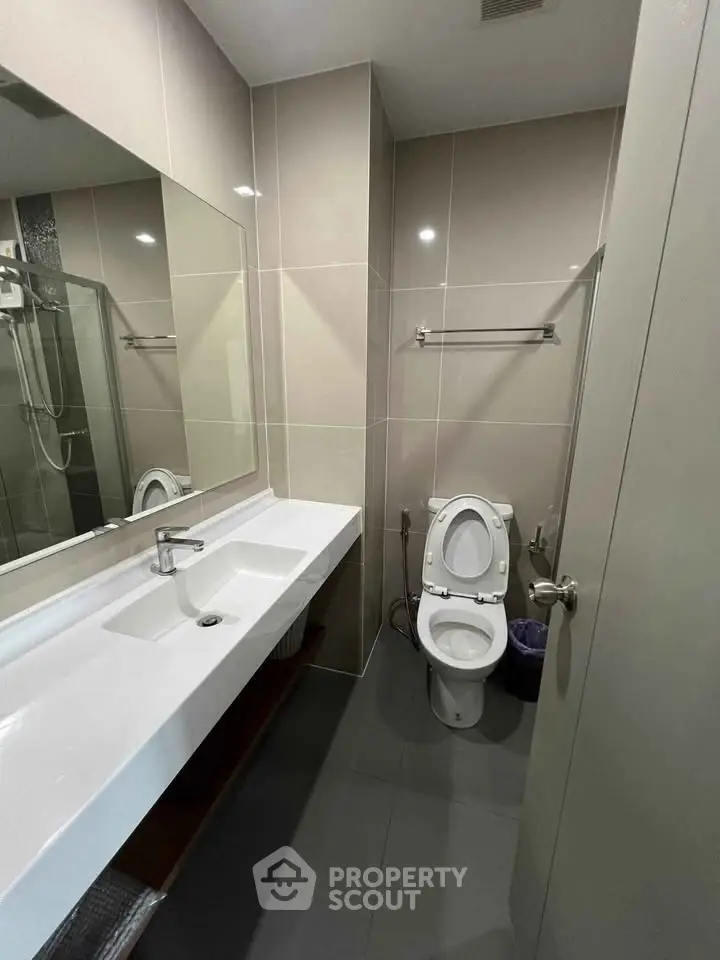 Modern bathroom with sleek design, featuring a large mirror and contemporary fixtures.