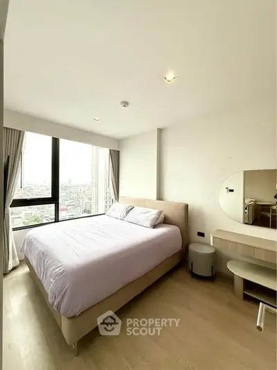 Modern bedroom with large windows offering city views, featuring a cozy bed and stylish furniture.