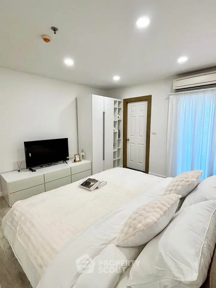 Modern bedroom with sleek design, featuring a cozy bed, TV, and ample storage in a bright, inviting space.