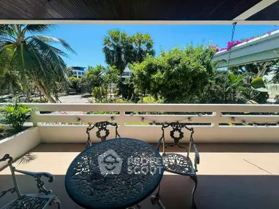 Charming balcony with elegant wrought iron furniture and lush garden view.