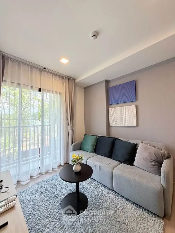 Modern living room with cozy sofa, stylish decor, and large window for natural light.