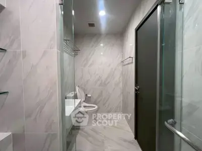 Modern bathroom with sleek marble tiles and glass shower enclosure