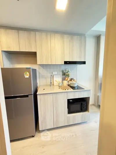 Modern compact kitchen with sleek cabinetry and stainless steel appliances in a stylish apartment.