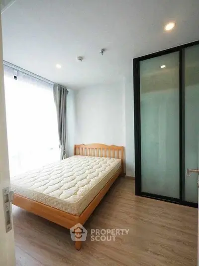Cozy bedroom with wooden bed frame and large window for natural light