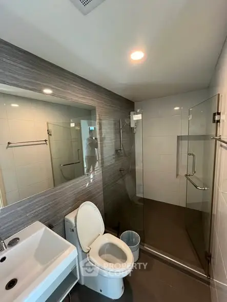 Modern bathroom with glass shower and sleek fixtures in contemporary apartment.
