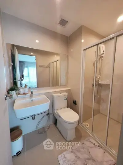 Modern bathroom with glass shower, sleek fixtures, and large mirror, offering a clean and contemporary design.