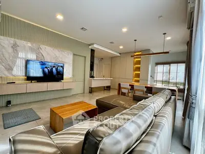 Luxurious modern living room with sleek design and open layout, featuring a large TV and stylish furniture.