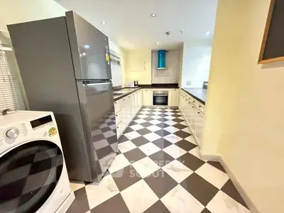 Spacious modern kitchen with sleek appliances and stylish checkered flooring.