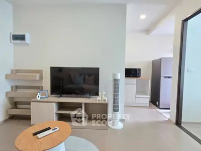 Modern living room with sleek furniture and open kitchen layout, featuring a TV and stylish decor.