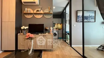 Modern living room with stylish decor and open kitchen layout, featuring a washing machine and elegant furnishings.