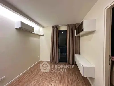 Modern minimalist room with wooden flooring and air conditioning, featuring a sleek wall-mounted cabinet and large window.
