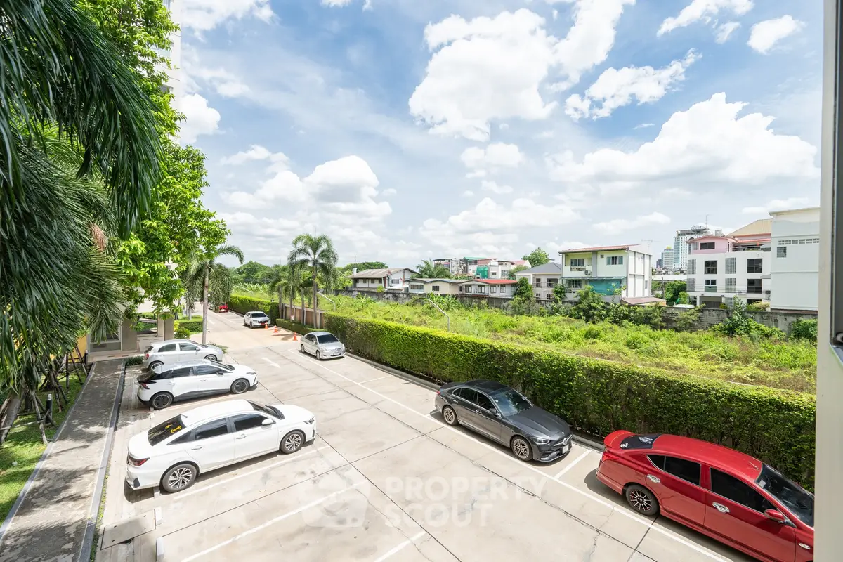 Spacious residential parking area with lush greenery and clear blue sky.
