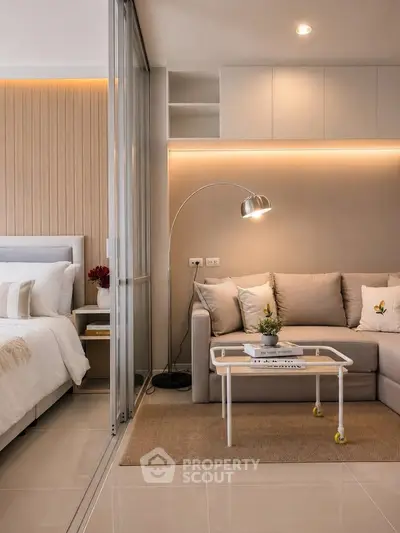 Modern living room with cozy sofa and stylish lighting next to a chic bedroom