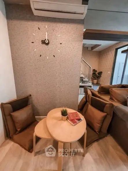 Cozy living room with modern decor, featuring a stylish wall clock and comfortable seating area.