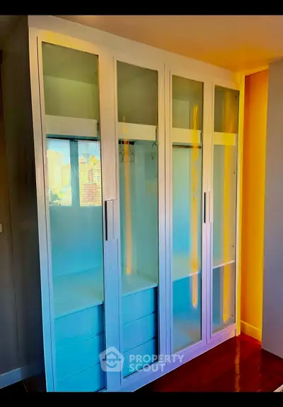Spacious modern wardrobe with glass doors in a stylish bedroom setting.