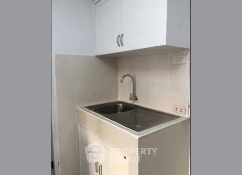 Compact kitchen area with sink and overhead cabinets in modern apartment.