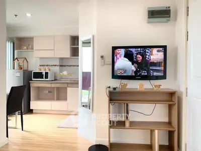 Modern apartment interior with open kitchen and wall-mounted TV, featuring sleek cabinetry and wooden flooring.