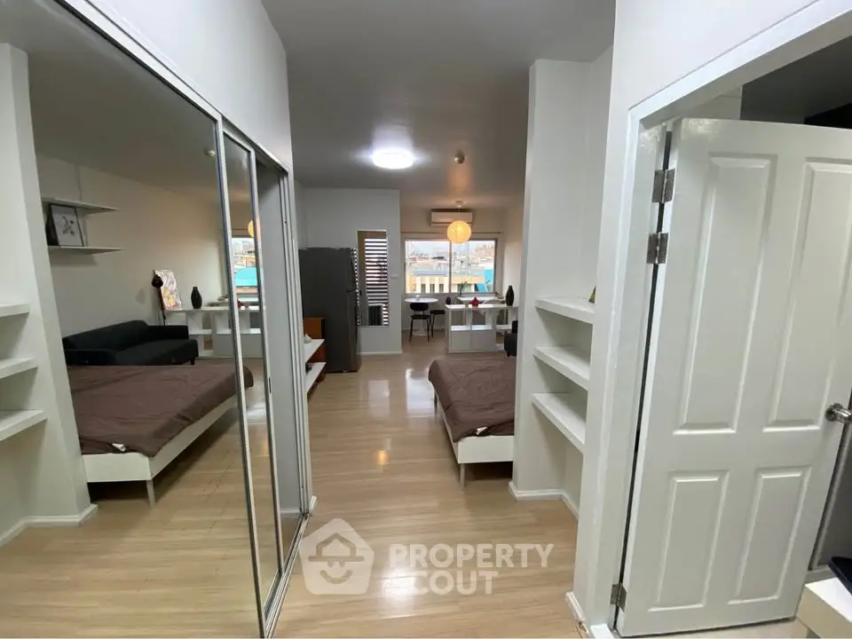 Modern studio apartment with mirrored closet and open layout, featuring sleek wooden flooring and contemporary decor.