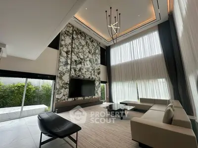 Luxurious modern living room with high ceilings, elegant chandelier, and floor-to-ceiling windows.