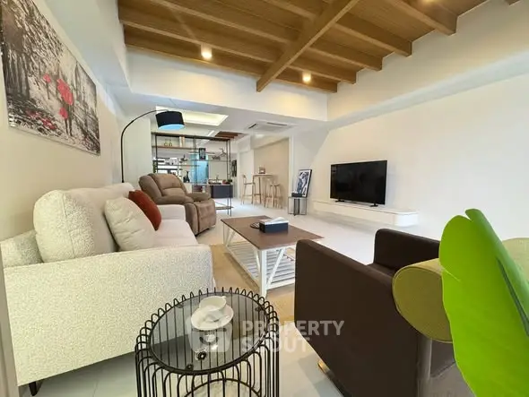 Spacious modern living room with stylish decor and wooden ceiling beams.