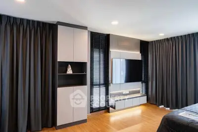 Modern bedroom with sleek TV setup and elegant curtains