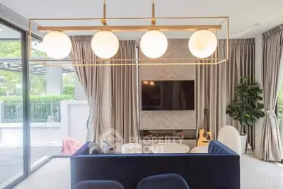 Modern living room with stylish lighting and large windows overlooking greenery.