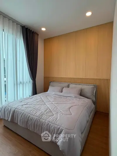 Modern bedroom with cozy bedding and elegant wooden paneling, featuring large windows with stylish curtains.