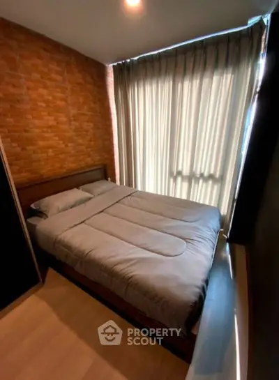 Cozy bedroom with brick accent wall and large window with curtains