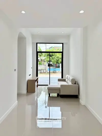 Spacious living room with modern sofa and large window offering natural light and outdoor view.