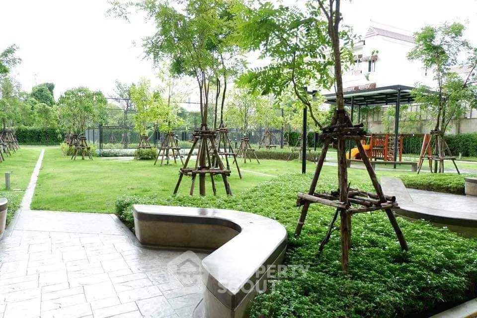 Lush green garden with modern landscaping and seating area in residential complex.