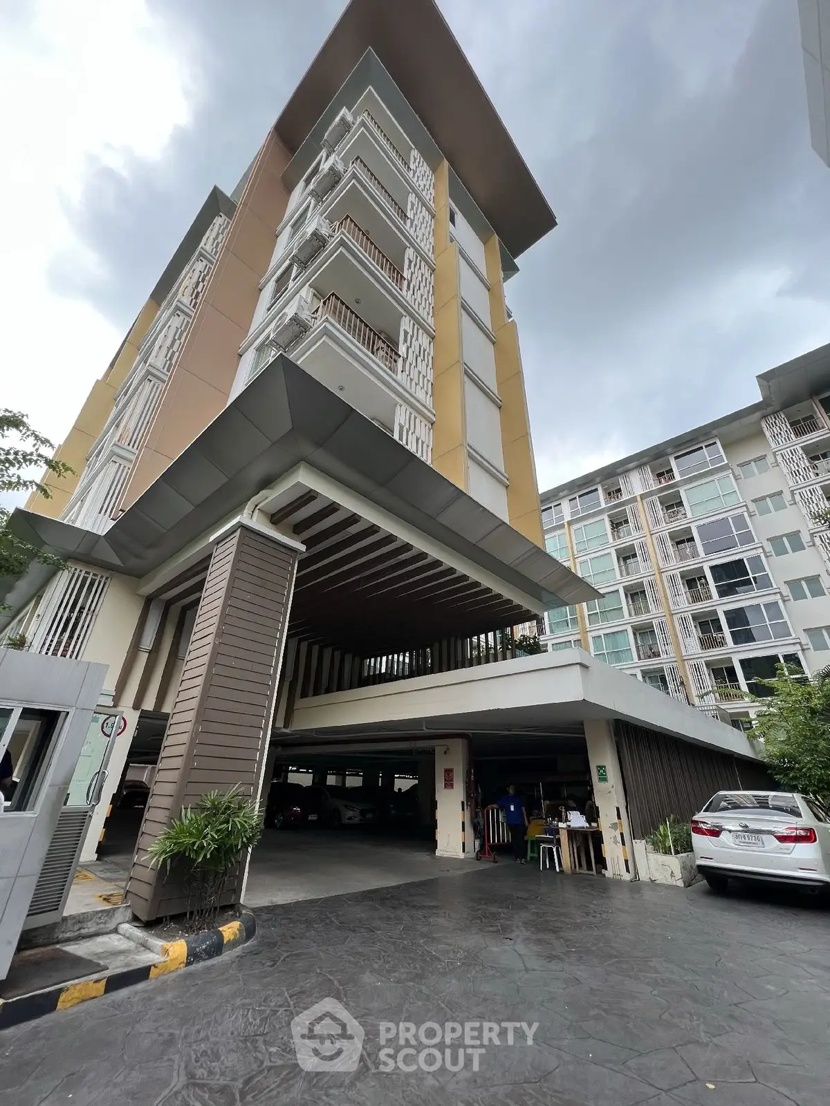 Modern multi-story residential building with parking area and sleek architectural design.