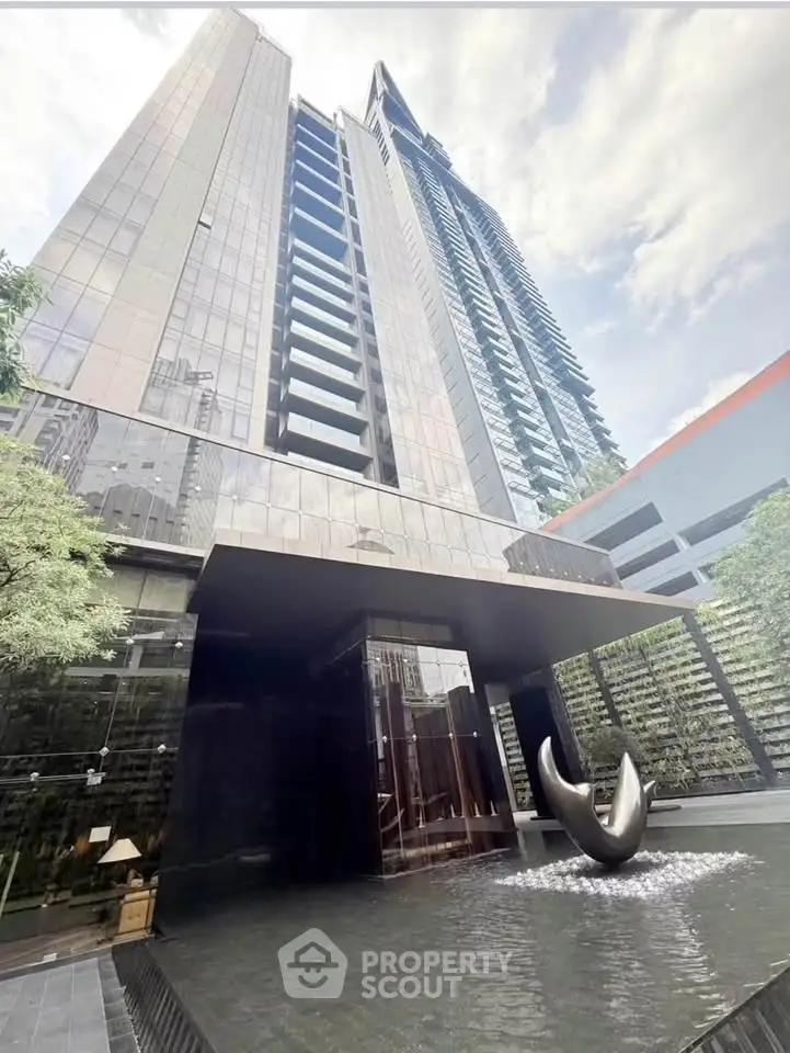 Stunning modern high-rise building with sleek entrance and water feature.