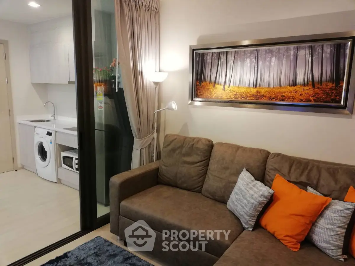 Modern living room with cozy sofa and adjacent laundry area in stylish apartment.