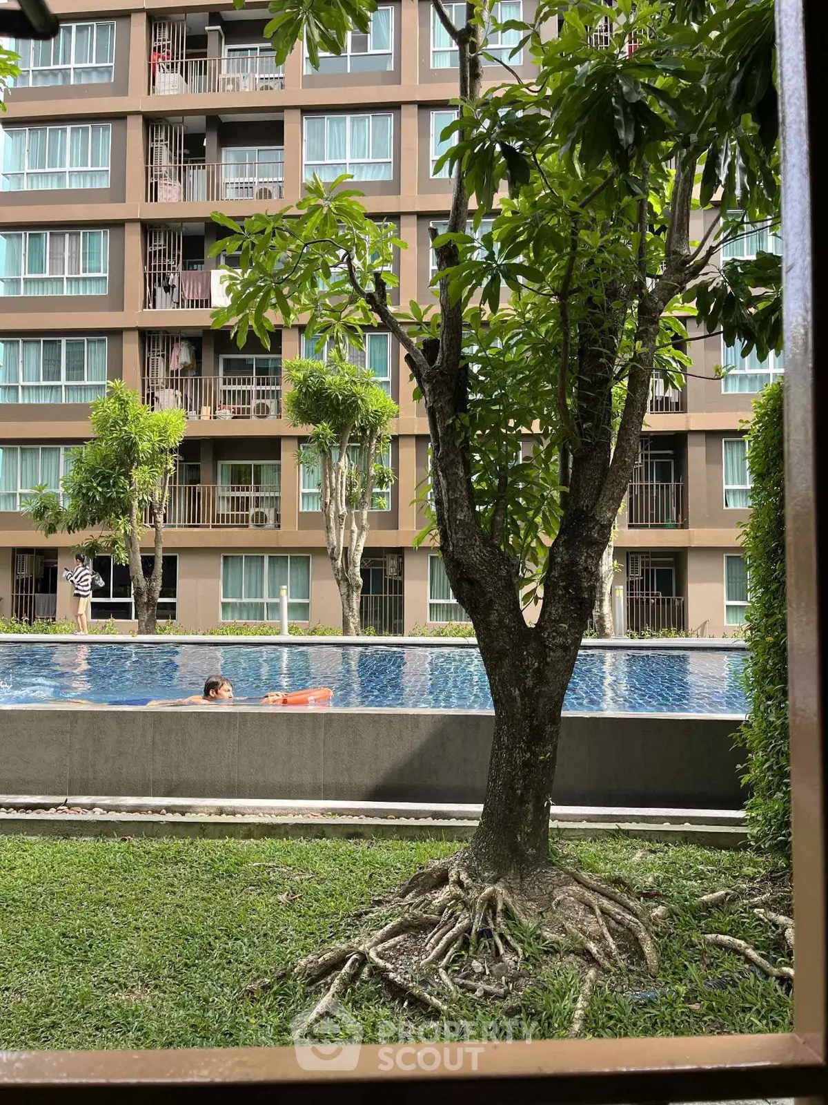 Modern apartment building with pool view and lush greenery