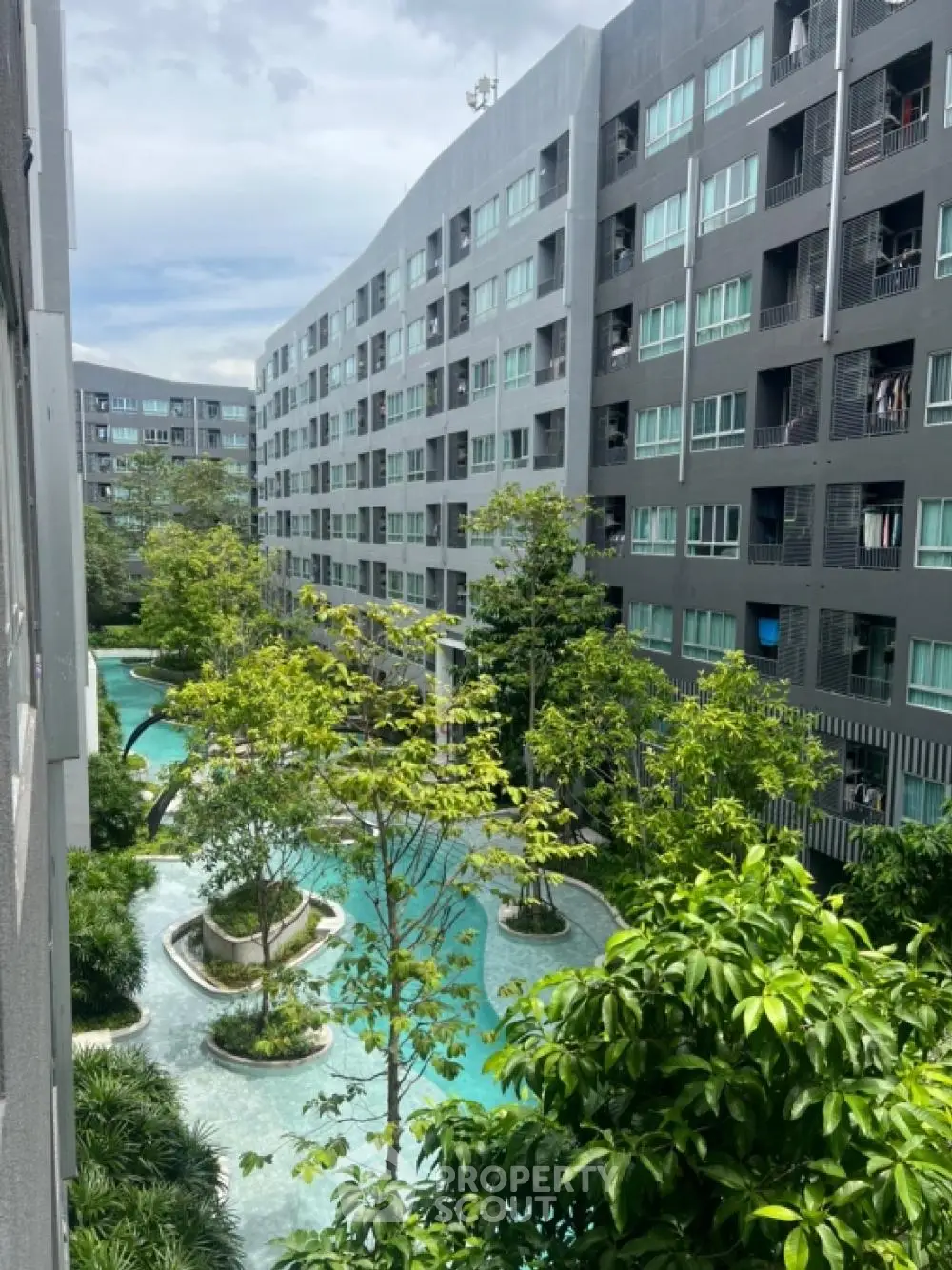 Modern apartment complex with lush garden and pool view, perfect for urban living.