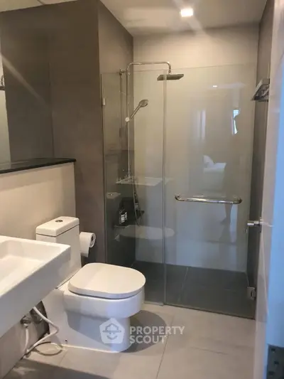 Modern bathroom with glass shower enclosure and sleek fixtures in a contemporary apartment.